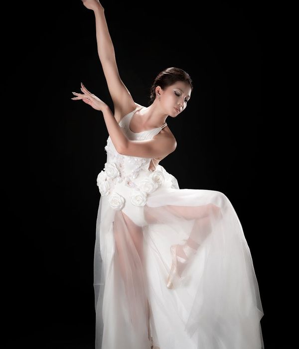 Woman performing a graceful cardio movement in a dark studio.